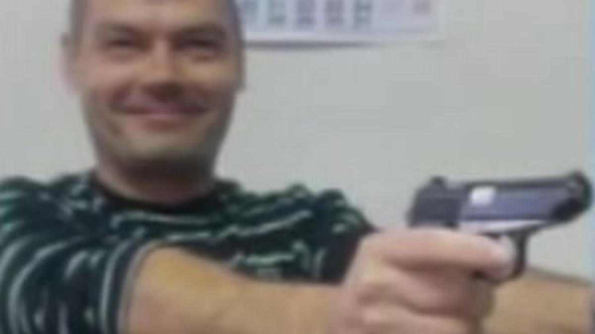 Distracţie cu arma din dotare: Un poliţist a postat pe internet poze în care apare cu două pistoale