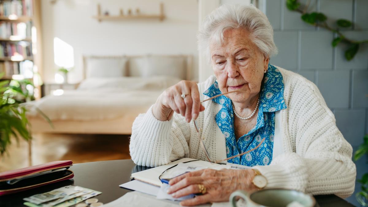 o femeie in varsta pensionara se uita pe facturi