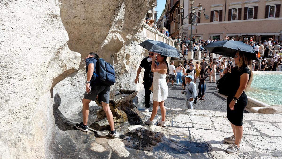 persoane cu umbrela la coada la apa in roma