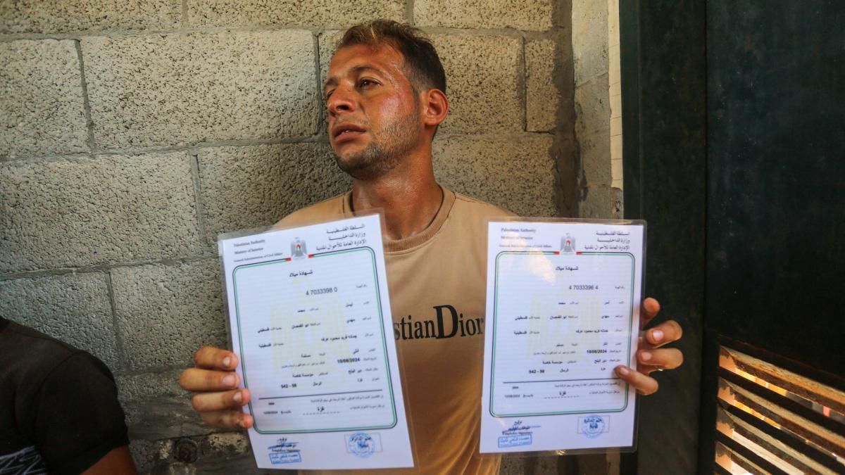 un barbat din gaza care tine in maini doua certifricate de nastere