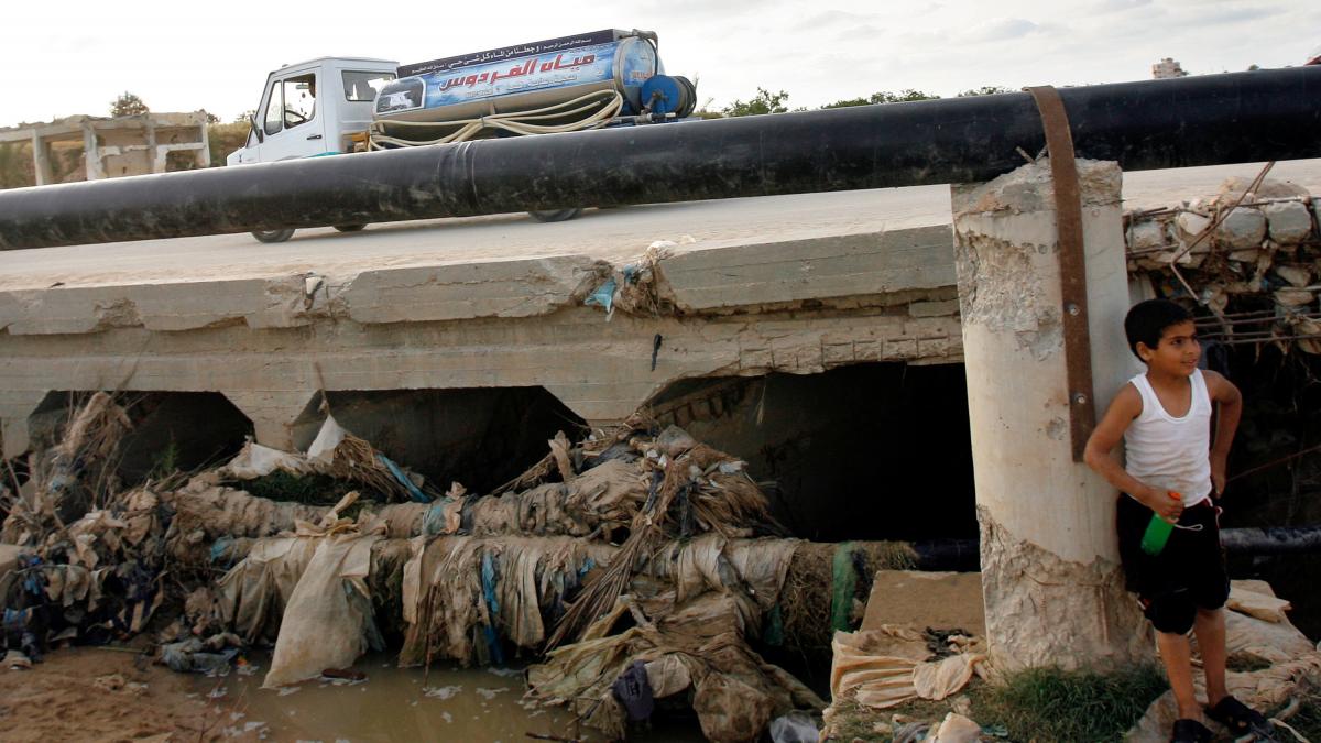 Masina de apa pe un drum din Gaza si un copil care sta ?ntr-o zona contaminata. 