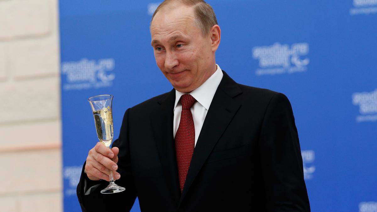 Vladimir Putin z?mbe?te cu un pahar de ?ampanie ?n m?n?. Foto: Getty Images