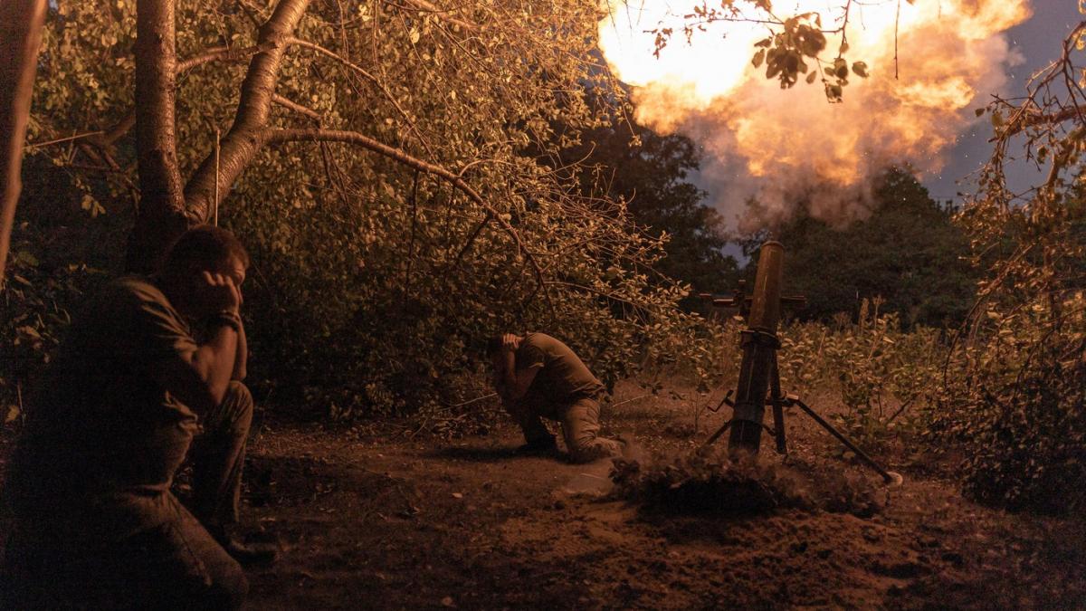 Soldati cu mainile la urechi intr-o zona de padure in timp ce un mortar trage focuri