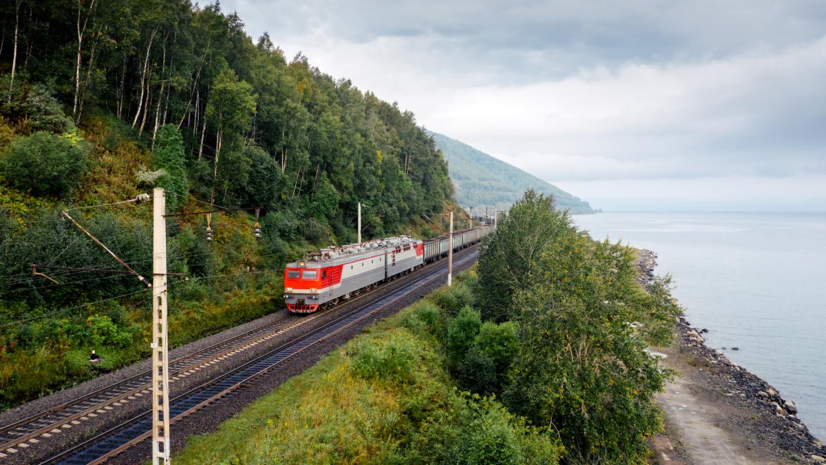 un tren transsiberian cu muntele in dreapta si lacul Baikal in stanga