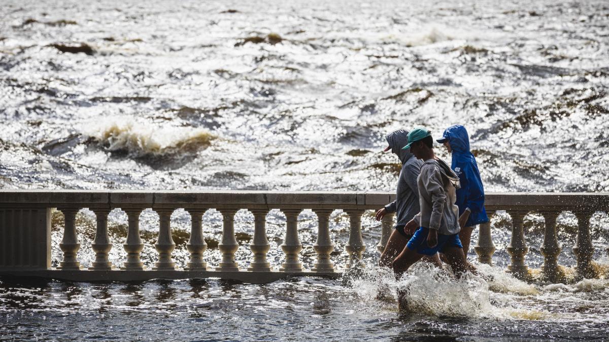 Oameni merg prin inundatii pe un pod