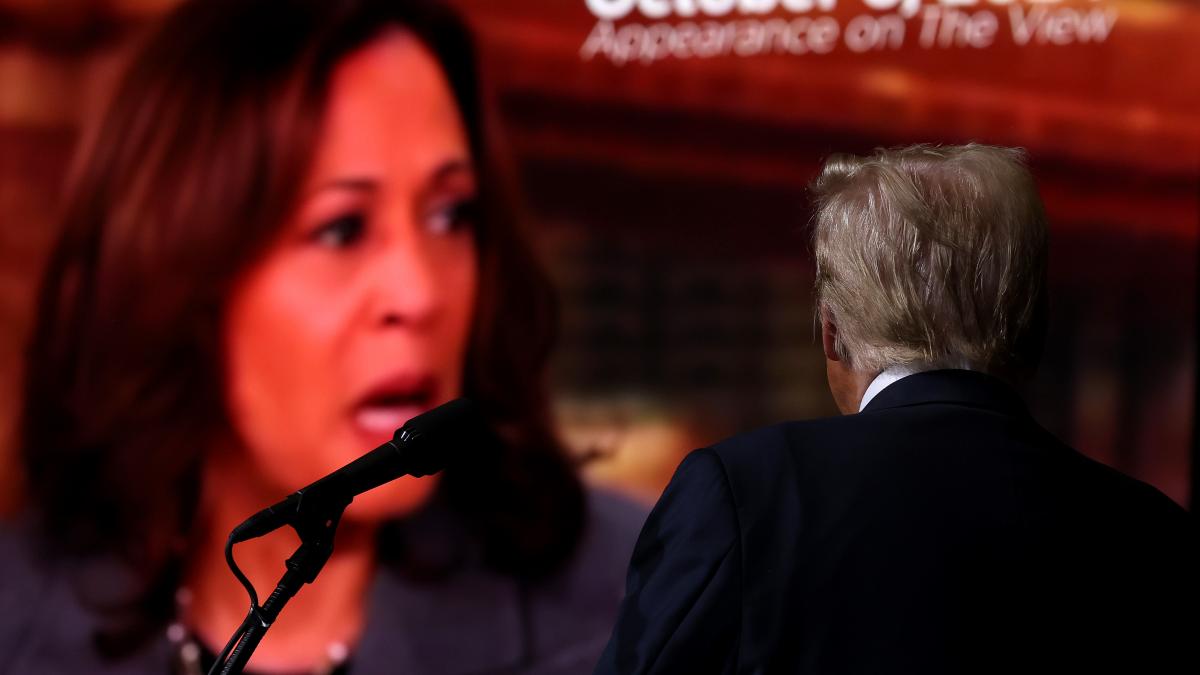 Donald Trump priveste spre un ecran in care apare Kamala Harris