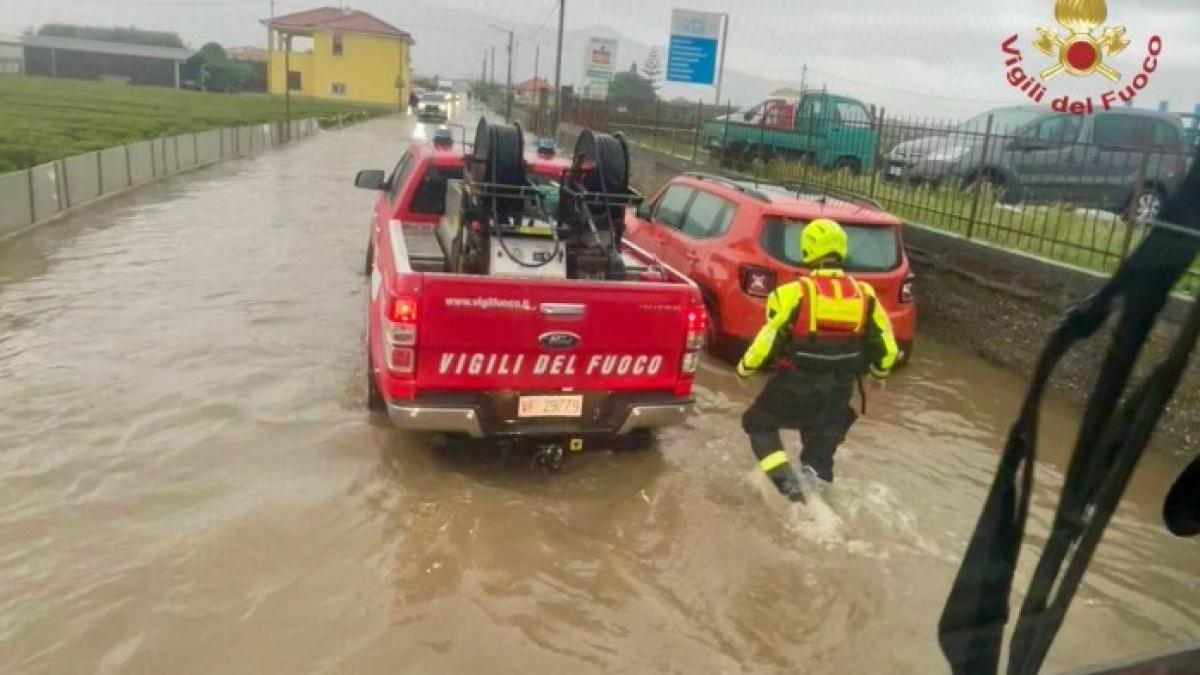 Un salvator merge prin apa mare spre o masina rosie