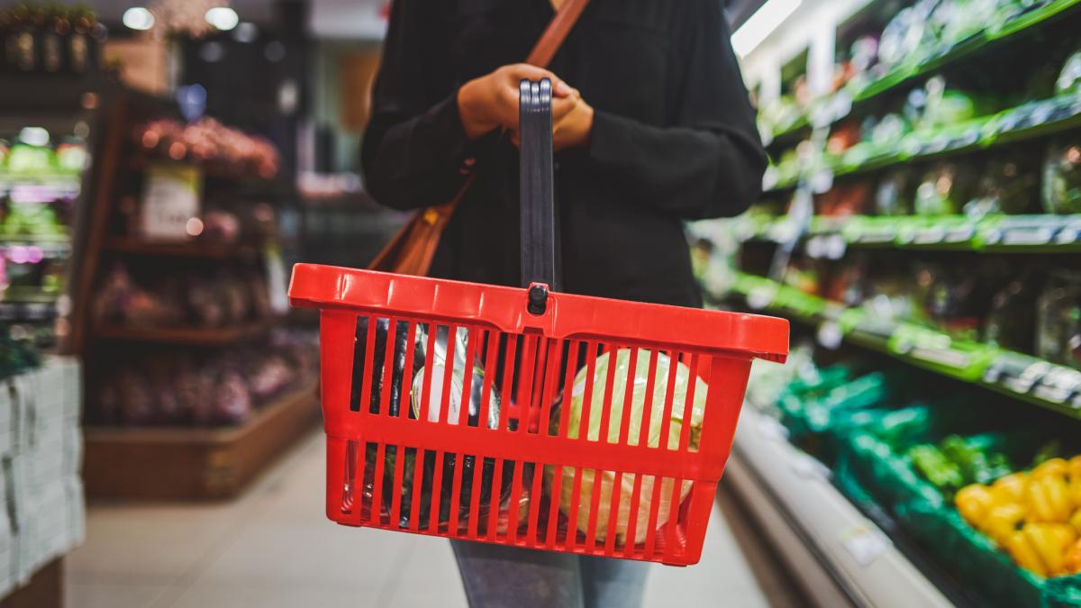 persoana cu un cos cu alimente in supermarket