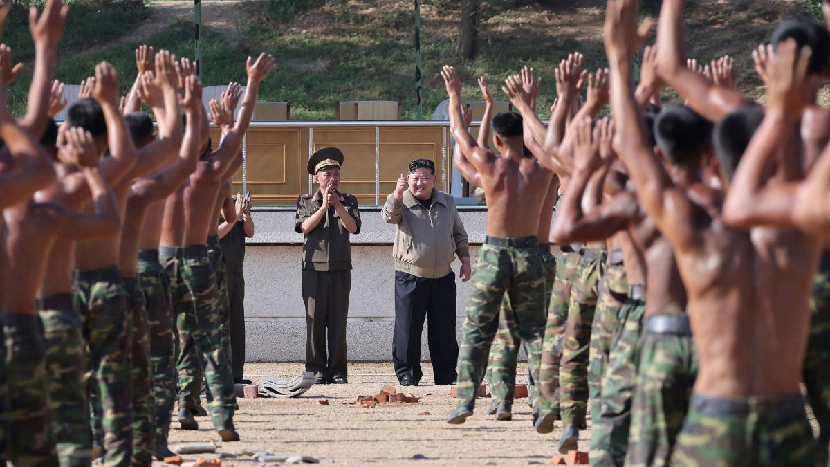 soldati nord coreeni dzbracati cu mainile in aer si kim jong un care le face fericit cu mana