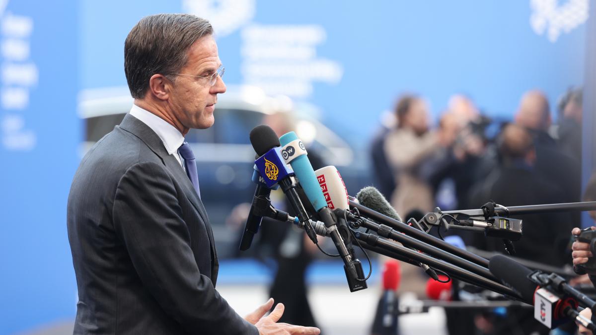 Mark Rutte din profil în fața unor microfoane.