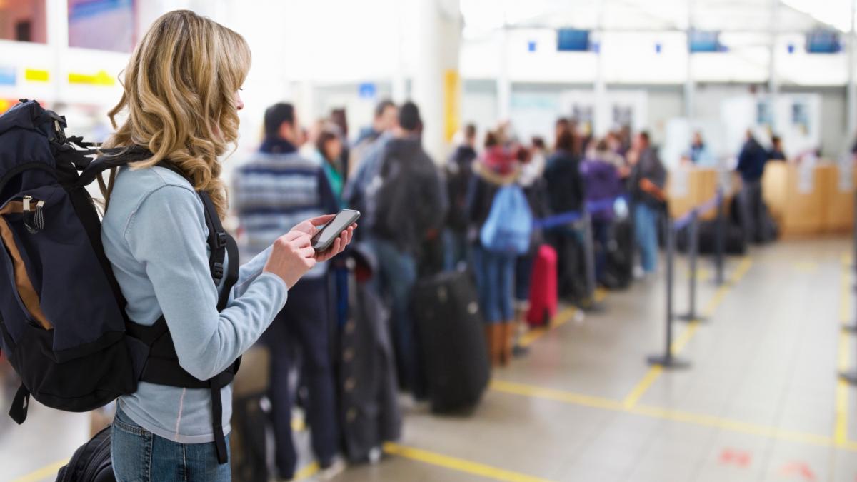 femeie care se uita pe telefon in aeroport