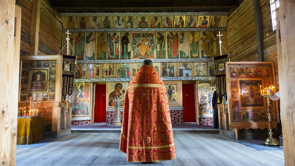 preot ortodox in fata altarului din biserica