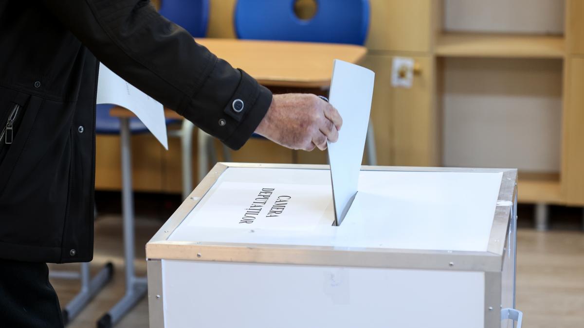 o persoana baga un buletin de vot in urna