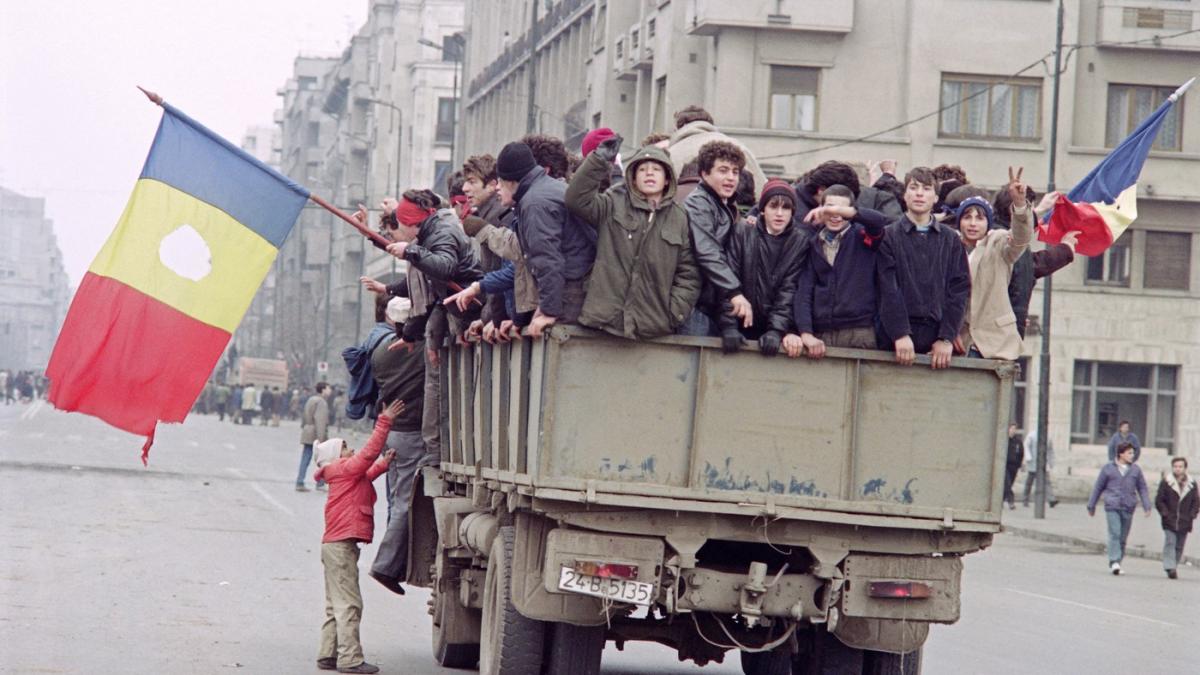 Revoluționari din 1989 cu steaguri cu gaura în locul unde se afla stema comunistă.