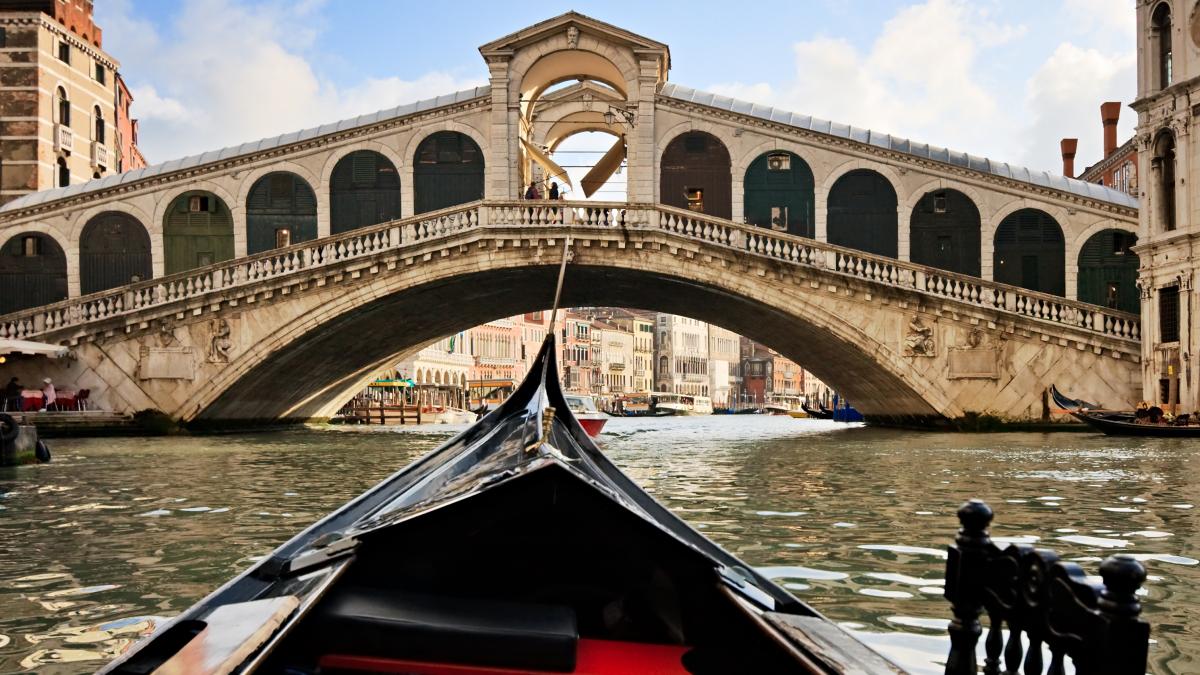 Botul unei gondole care merge pe apa spre Ponte di Rialto la Venetia