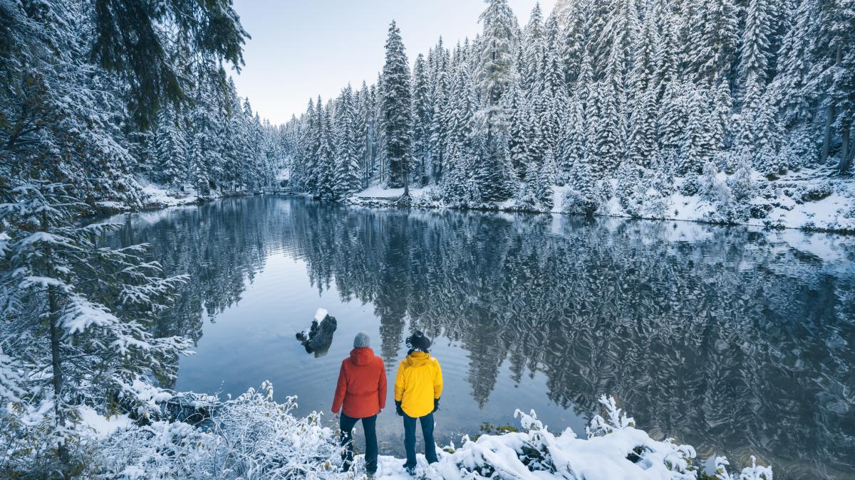 doua persoane pe malul unui lac, iarna