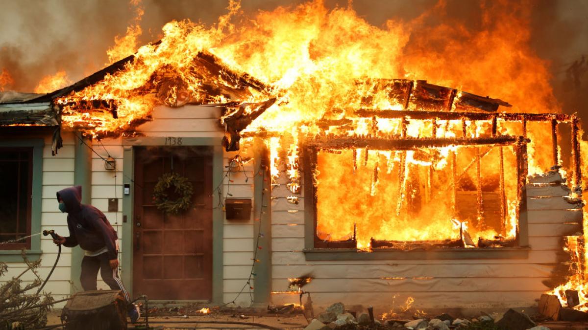 O casa arde in Los Angeles si proprietarul incearca sa opreasca flacarile cu un furtun de gradina foto getty images