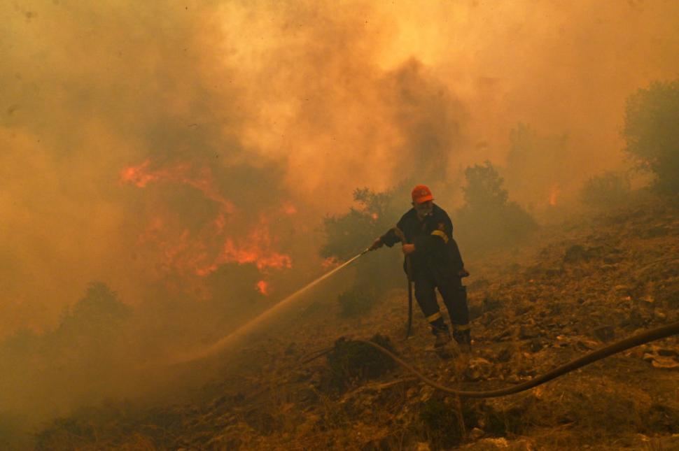 un pompier care incearca sa stinga un incendiu de vegetatie in grecia