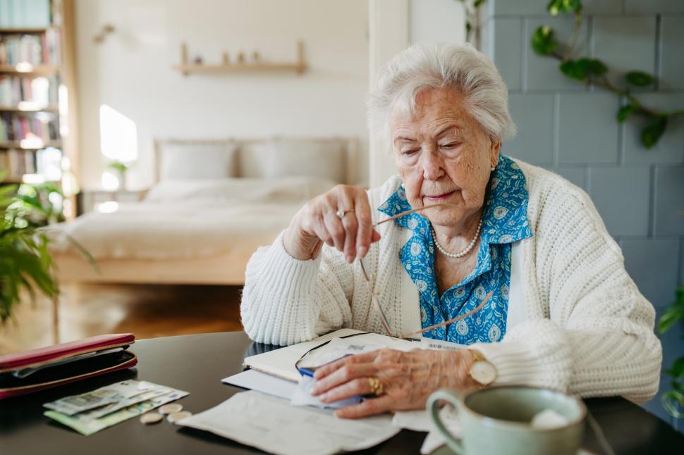 o femeie in varsta pensionara se uita pe facturi