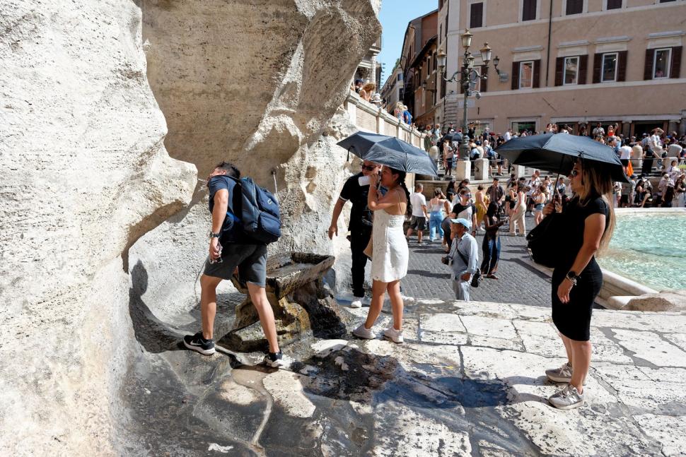 persoane cu umbrela la coada la apa in roma