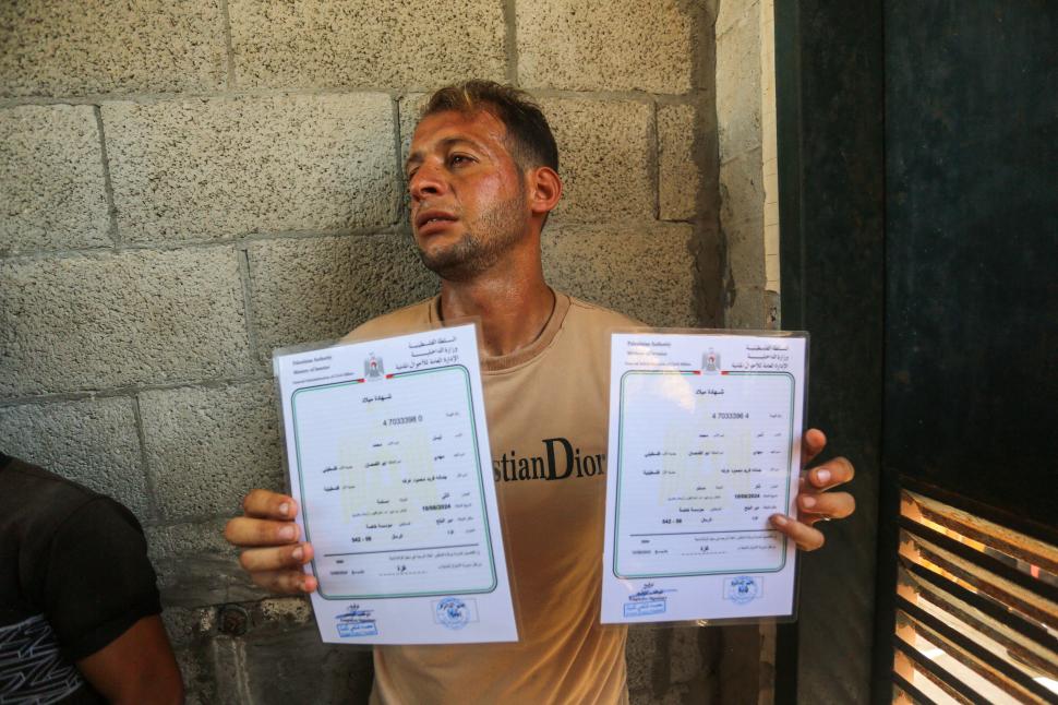 un barbat din gaza care tine in maini doua certifricate de nastere