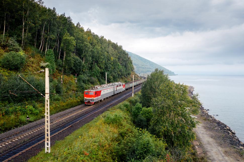 un tren transsiberian cu muntele in dreapta si lacul Baikal in stanga