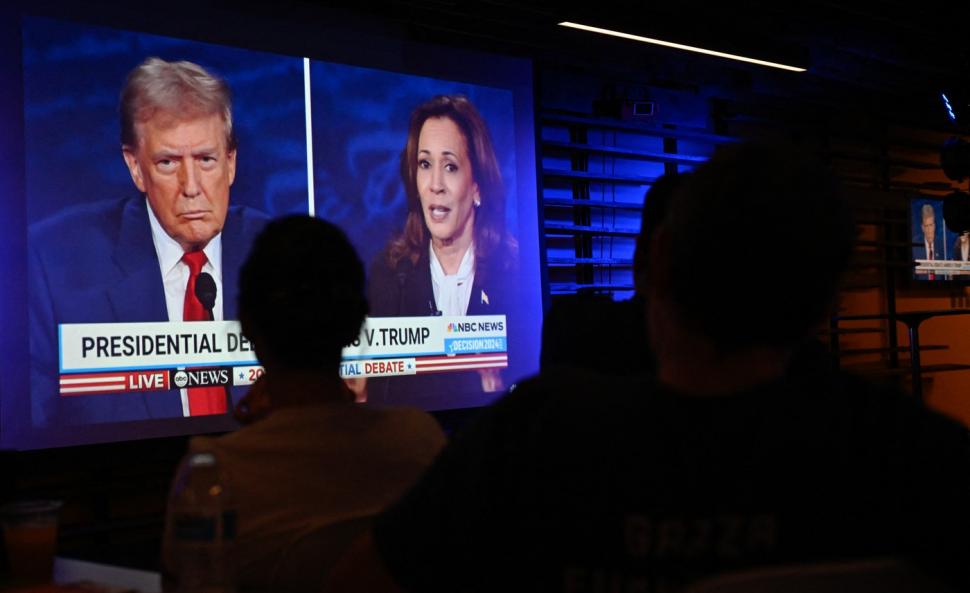 oameni se uita la tv la dezbaterea trump-harris