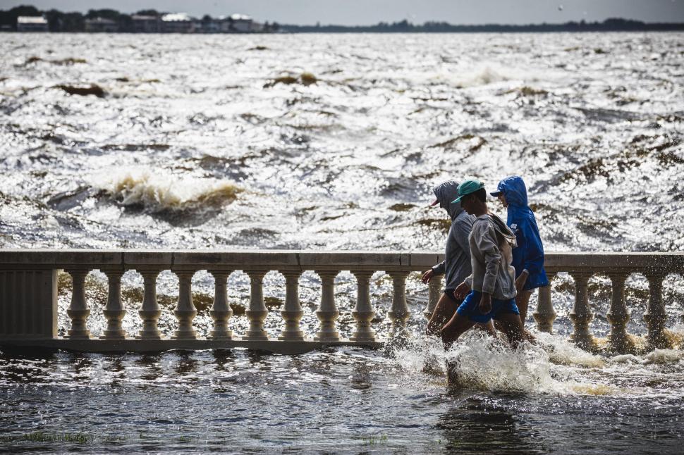 Oameni merg prin inundatii pe un pod