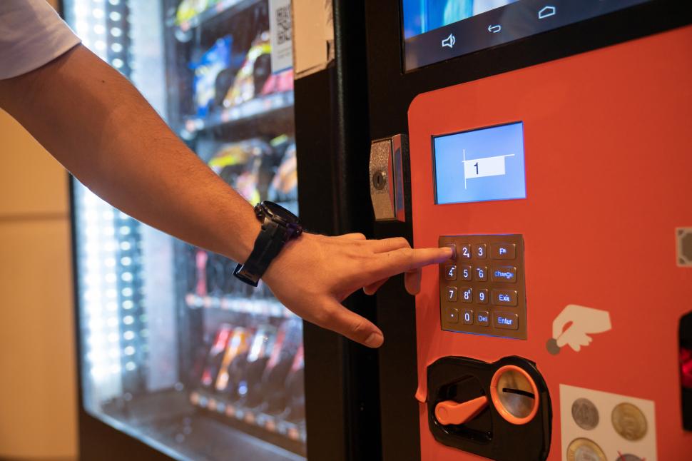 o persoana alege un produs de la un automat de gustari