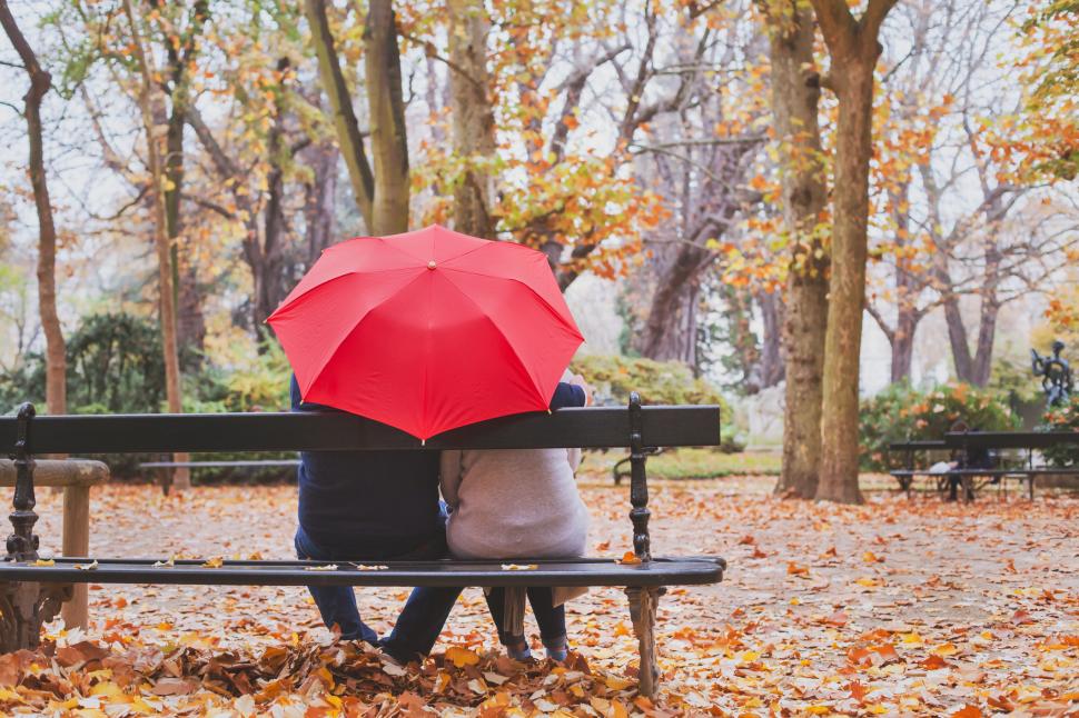 cuplu cu o umbrela pe banca in parc